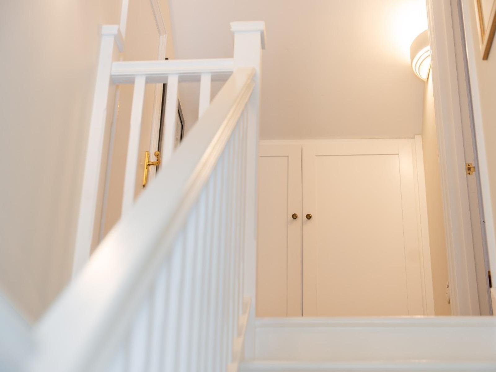White fitted cupboard built into a landing alcove at the top of a staircase