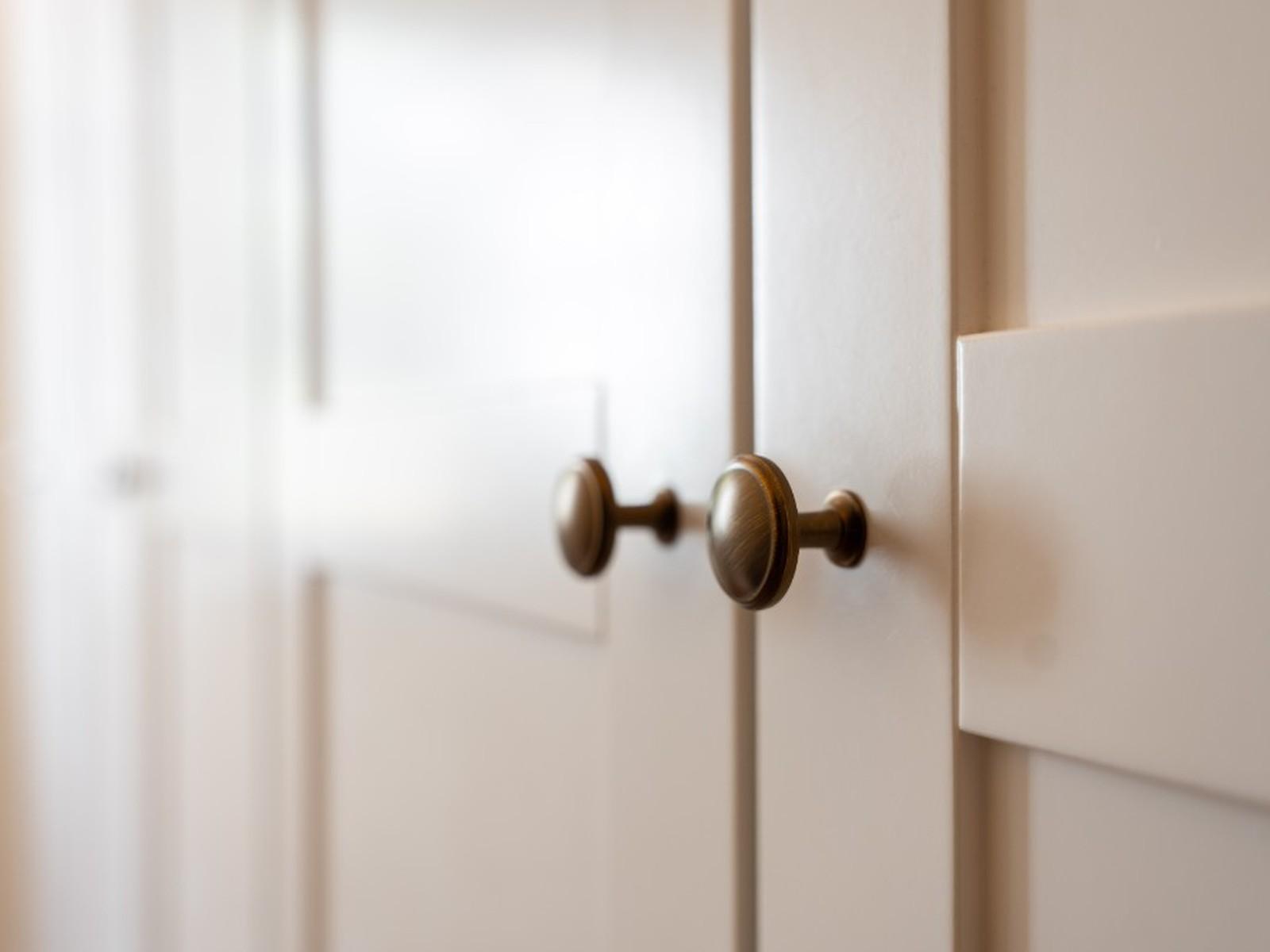 Close-up of cream Shaker wardrobe doors with antique brass knobs