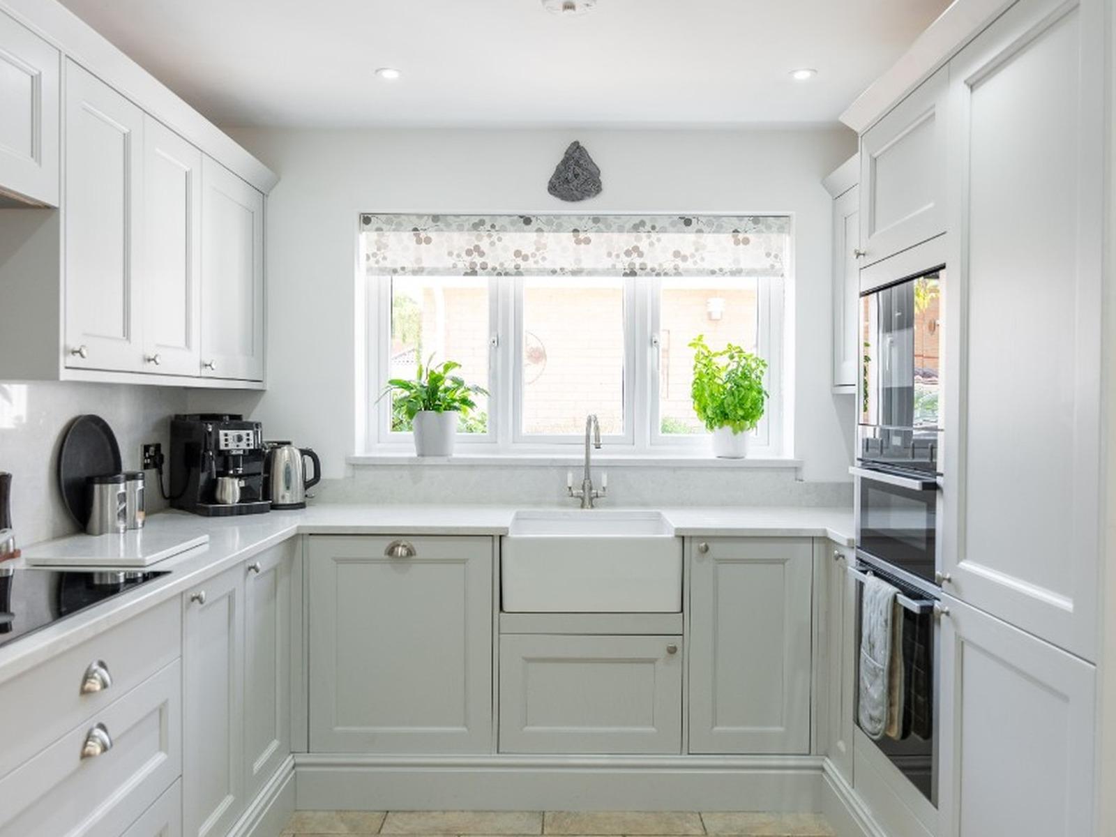 U-shaped light grey Shaker kitchen with a Belfast sink under the window