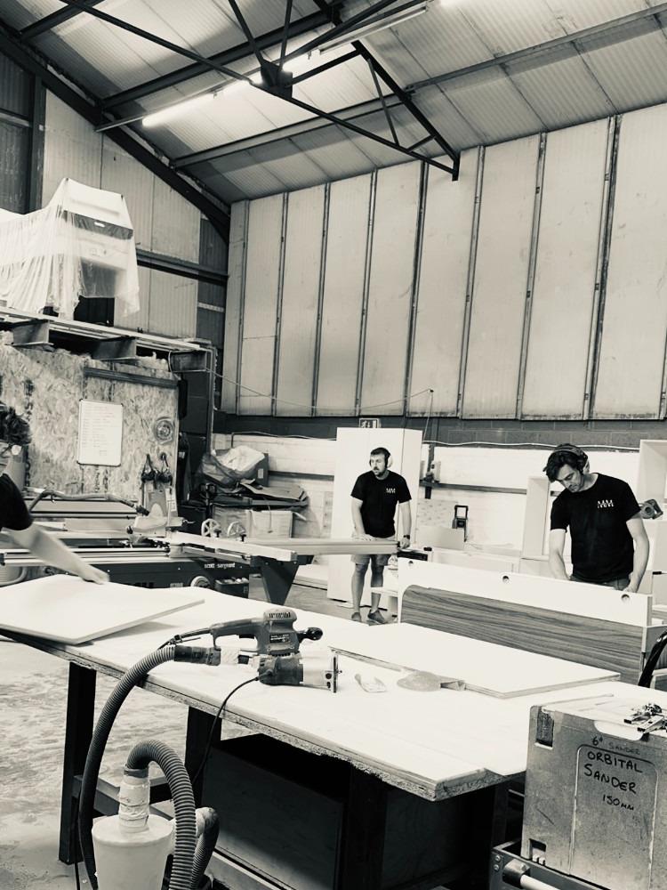 Black and white photograph of the Marston Made workshop with joiners at workbenches and machinery
